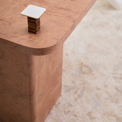 Mesa con una estructura ortogonal que se suaviza con sutiles curvas en el tablero y la base, creando una sensación de armonía. Color ocre.